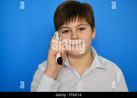 Teen boy talking en radiotéléphonie sur fond bleu Banque D'Images