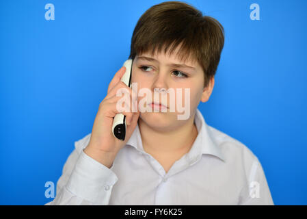 Teen boy talking en radiotéléphonie sur fond bleu Banque D'Images