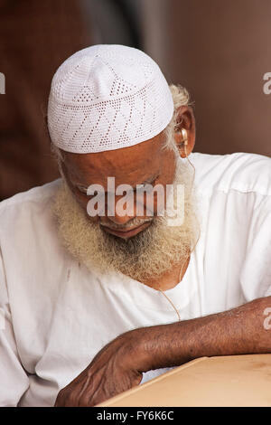 Little India, Singapour-2008. Vieux Hindi homme avec une barbe et moustache grise dans une robe blanche traditionnelle et le capuchon avec une audience ai Banque D'Images