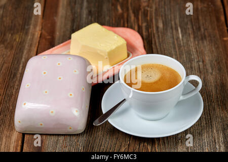 Café et le beurre sur un plat sur une table en bois brun Banque D'Images