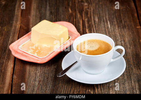 Café et le beurre sur un plat sur une table en bois brun Banque D'Images