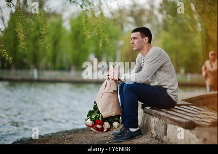 Homme avec un bouquet de fleurs en attente de sa petite amie. Déclaration d'amour et demande en mariage Banque D'Images