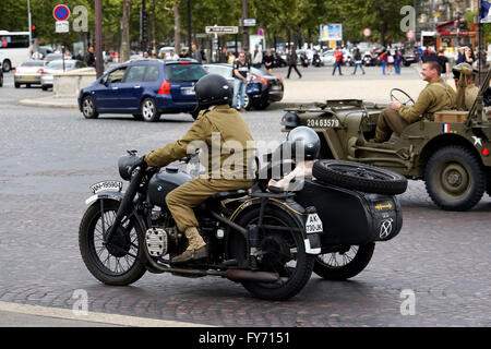 Des gens habillés dans WWII G.I. uniforms équitation guerre Jeep et moto sur l'Avenue des Champs-Elysees, Paris France Banque D'Images
