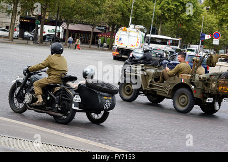 Des gens habillés dans WWII G.I. uniforms équitation guerre Jeep et moto sur l'Avenue des Champs-Elysees, Paris France Banque D'Images