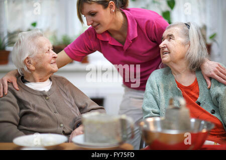 Deux femmes âgées, 78 ans et 88 ans, et d'un accompagnant pour les personnes âgées, 31 ans, les activités de loisirs dans une maison de soins infirmiers Banque D'Images