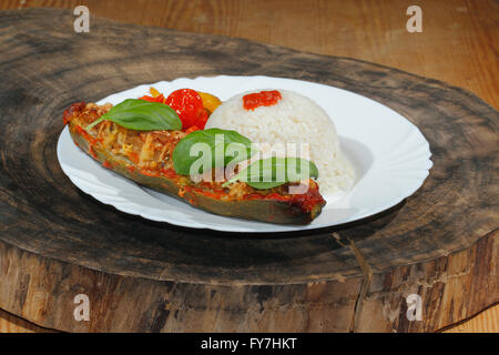 Courgette farcie, riz, compotée de poivrons et tomates, légumes, salade et décorer avec des feuilles de basilic sur une plaque Banque D'Images