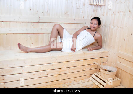 Femme enveloppée dans une serviette blanche en relaxant sauna en bois Prix Banque D'Images