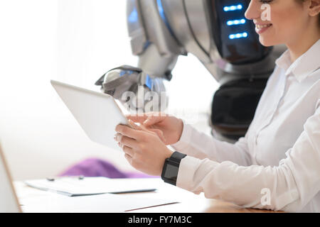 Fille positive à l'aide de tablette avec robot Banque D'Images