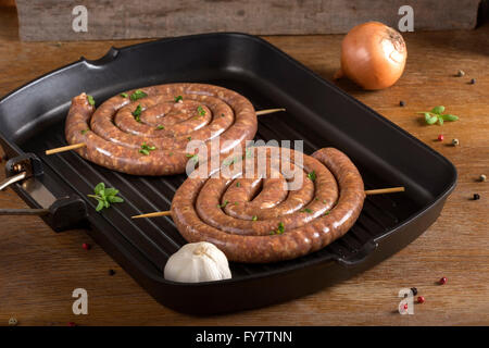 Deux saucisses crues en spirale sur un pan grillé Banque D'Images