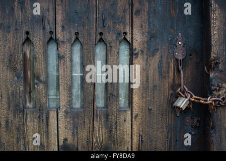 Chaîne cadenassé, verrouillé la porte en bois avec des fentes d'une fenêtre en arc en castleton ferme outhouse, Derbyshire. Banque D'Images