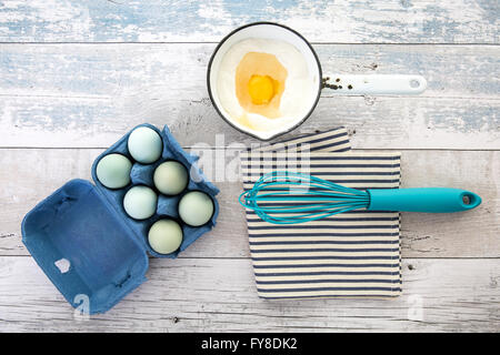 Oeufs dans une boîte avec un fouet sur une table rustique en bois au-dessus de top shot Banque D'Images