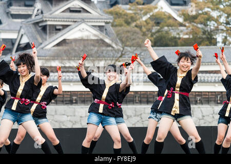 Japanese female dance troupe d'adolescentes, holding naruko, danser sur scène en plein air avec Château Kumamoto derrière eux, au cours de la fête de Yosakoi. Banque D'Images