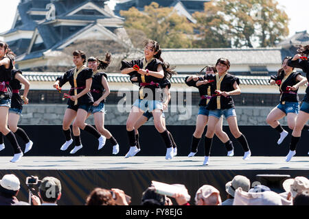 Japanese female dance troupe d'adolescentes, holding naruko, danser sur scène en plein air avec Château Kumamoto derrière eux, au cours de la fête de Yosakoi. Banque D'Images