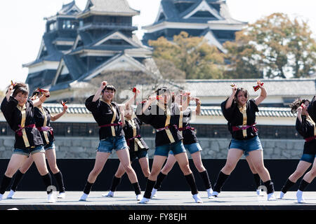 Japanese female dance troupe d'adolescentes, holding naruko, danser sur scène en plein air avec Château Kumamoto derrière eux, au cours de la fête de Yosakoi. Banque D'Images