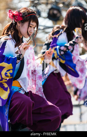 Les jeunes Japonais femme fleur rouge dans les cheveux, une partie de l'équipe de danse, danse en costumes colorés au cours de danse Yosakoi Festival à Kumamoto, au Japon. Banque D'Images