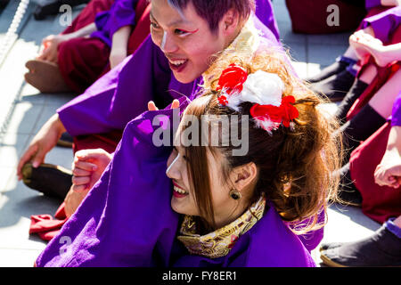 Regardant le jeune homme assis à côté de jeune femme partageant une blague ensemble. Habillé en yukata pourpre au cours de danse Yosakoi Festival. Banque D'Images