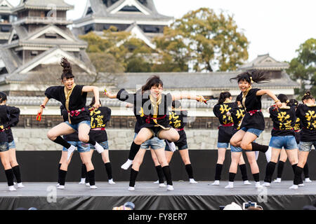 Japanese female dance troupe d'adolescentes, holding naruko, danser sur scène en plein air avec Château Kumamoto derrière eux, au cours de la fête de Yosakoi. Banque D'Images