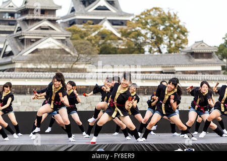 Japanese female dance troupe d'adolescentes, holding naruko, danser sur scène en plein air avec Château Kumamoto derrière eux, au cours de la fête de Yosakoi. Banque D'Images