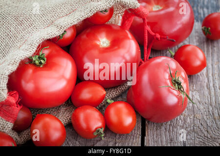 Des tomates bien mûres dans un sac sur la table en bois Banque D'Images