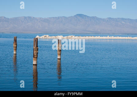 Posts reflètent dans l'eau sur un jour brumeux de l'été à Salton Sea en Californie Banque D'Images