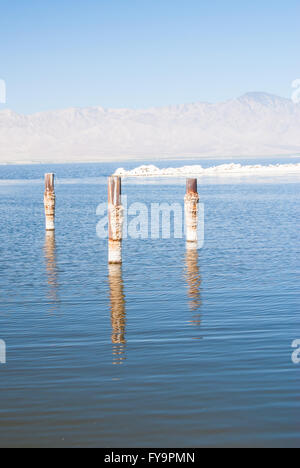 Posts reflètent dans l'eau sur un jour brumeux de l'été à Salton Sea en Californie Banque D'Images
