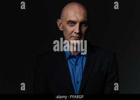 Portrait of handsome businessman en chemise bleue et veste sur fond noir Banque D'Images