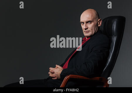 Portrait of businessman sitting in chaise de bureau et à la caméra à plus de fond noir Banque D'Images