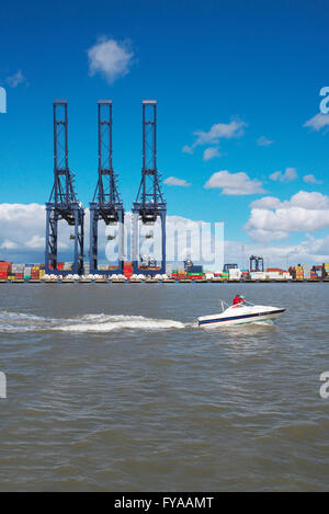 Petit bateau de moteurs sur la mer du Nord au-delà de la grandes grues du port de Felixstowe, car ils demeurent vides pendant la récession Banque D'Images