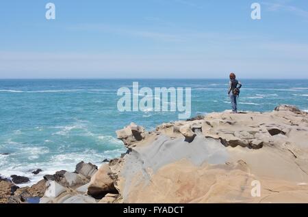 Une femme debout seul sur le bord d'une falaise rocheuse à Salt Point State Park, sur la côte nord de la Californie. Banque D'Images