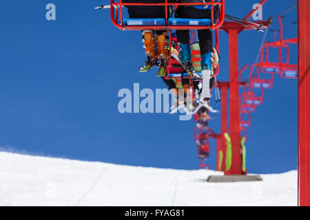 Les skieurs prendre du repos et de monter sur la crête d'une piste de ski avec remontées mécaniques rouge dans les montagnes de roumain Banque D'Images