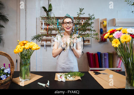 Jeune femme amusante joyeuse faire fleuriste bouquet et s'amusant dans le magasin de fleurs Banque D'Images