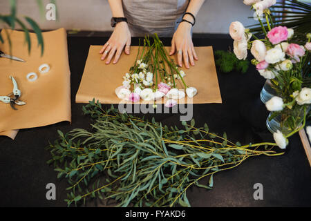 Vue de dessus de mains de female florist Conception et création des fleurs'' sur le tableau noir Banque D'Images