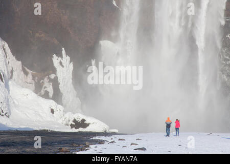 Les touristes en face de Skogafoss, 63 m de haut situé sur la cascade de la rivière Skógá en hiver, l'Islande, Skógar Banque D'Images