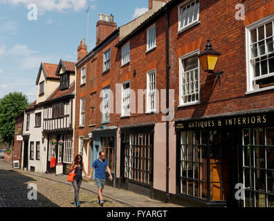 Jeune couple marche vers le haut de la rue médiévale de Elm Hill, à Norwich, Norfolk, Angleterre Banque D'Images