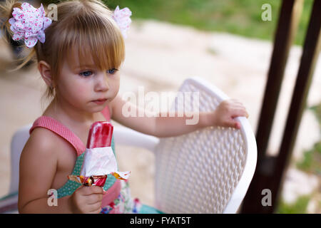 Petite fille mange de grandes glaces de consommation dans le parc. Portrait de profil avec selective focus Banque D'Images