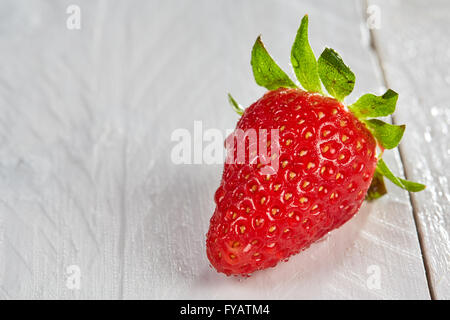 Macro shot of fresh red strawberry avec gouttes d'eau sur un tableau blanc Banque D'Images