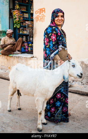 Femme indienne pose pour photo comme elle marche le long de la rue avec bouc Banque D'Images