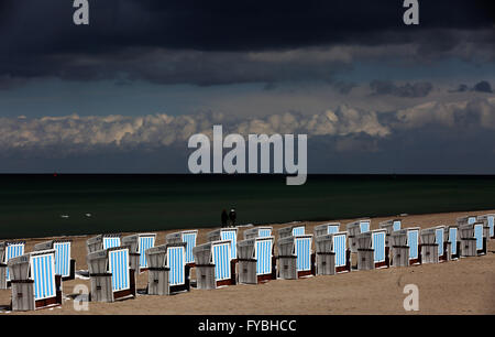 Rostock-Warnemuende, Allemagne. Apr 25, 2016. Des nuages sombres se déplacent sur des chaises de plage à baldaquin debout dans le soleil en Rostock-Warnemuende, Allemagne, 25 avril 2016. Un mélange de pluie, de neige et de grésil de douches avec sun entre-temps fait pour avril classique. Photo : BERND WUESTNECK/dpa/Alamy Live News Banque D'Images