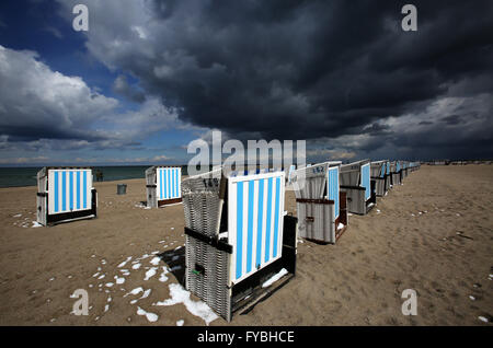 Rostock-Warnemuende, Allemagne. Apr 25, 2016. Des nuages sombres se déplacent sur des chaises de plage à baldaquin debout dans le soleil en Rostock-Warnemuende, Allemagne, 25 avril 2016. Un mélange de pluie, de neige et de grésil de douches avec sun entre-temps fait pour avril classique. Photo : BERND WUESTNECK/dpa/Alamy Live News Banque D'Images