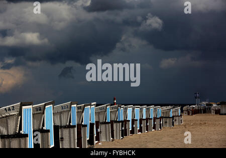 Rostock-Warnemuende, Allemagne. Apr 25, 2016. Des nuages sombres se déplacent sur des chaises de plage à baldaquin debout dans le soleil en Rostock-Warnemuende, Allemagne, 25 avril 2016. Un mélange de pluie, de neige et de grésil de douches avec sun entre-temps fait pour avril classique. Photo : BERND WUESTNECK/dpa/Alamy Live News Banque D'Images