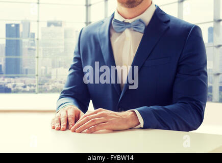 Portrait de l'homme en costume et nœud papillon à table Banque D'Images