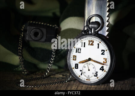 Montre de poche avec fusil et couteau, camuflage sur sol en bois Banque D'Images