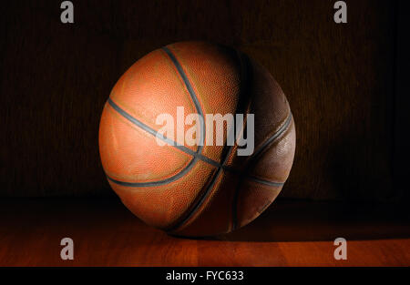 Ballon de basket-ball dans le plancher en bois foncé Banque D'Images