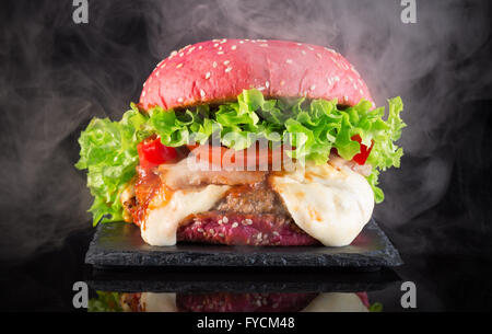 Big Red hamburger avec de la fumée sur un tableau d'ardoise. Banque D'Images