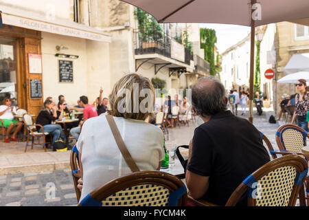 Couple d'âge moyen assis à un café de la chaussée et en regardant les passants, Lourmarin, Vaucluse, Provence-Alpes-Côte d'Azur, France Banque D'Images