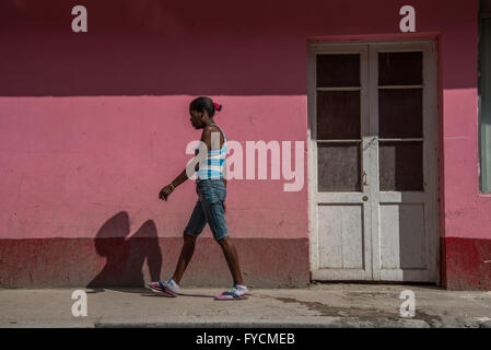 Une femme seule marchant dans une rue de Cuba avec un mur derrière rose peint de couleurs vives. La Vieille Havane, Cuba Banque D'Images