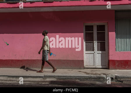 Un homme seul marche dans une rue avec un mur derrière rose peint de couleurs vives. La Vieille Havane, Cuba Banque D'Images