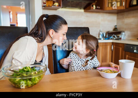 Mère et fille dans la cuisine, manger ensemble spaghetti Banque D'Images