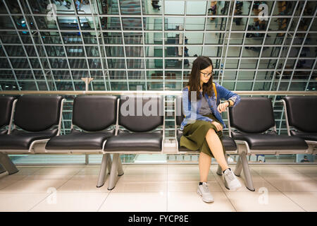 Belle fille asiatique regardant sa montre, en attendant l'embarquement, l'avion concept de temps Banque D'Images