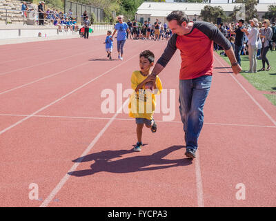 Un père tient la main de son fils handicapé dans une course à la tenue des Jeux olympiques spéciaux du sud de la Californie à Santa Barbara, CA. Banque D'Images